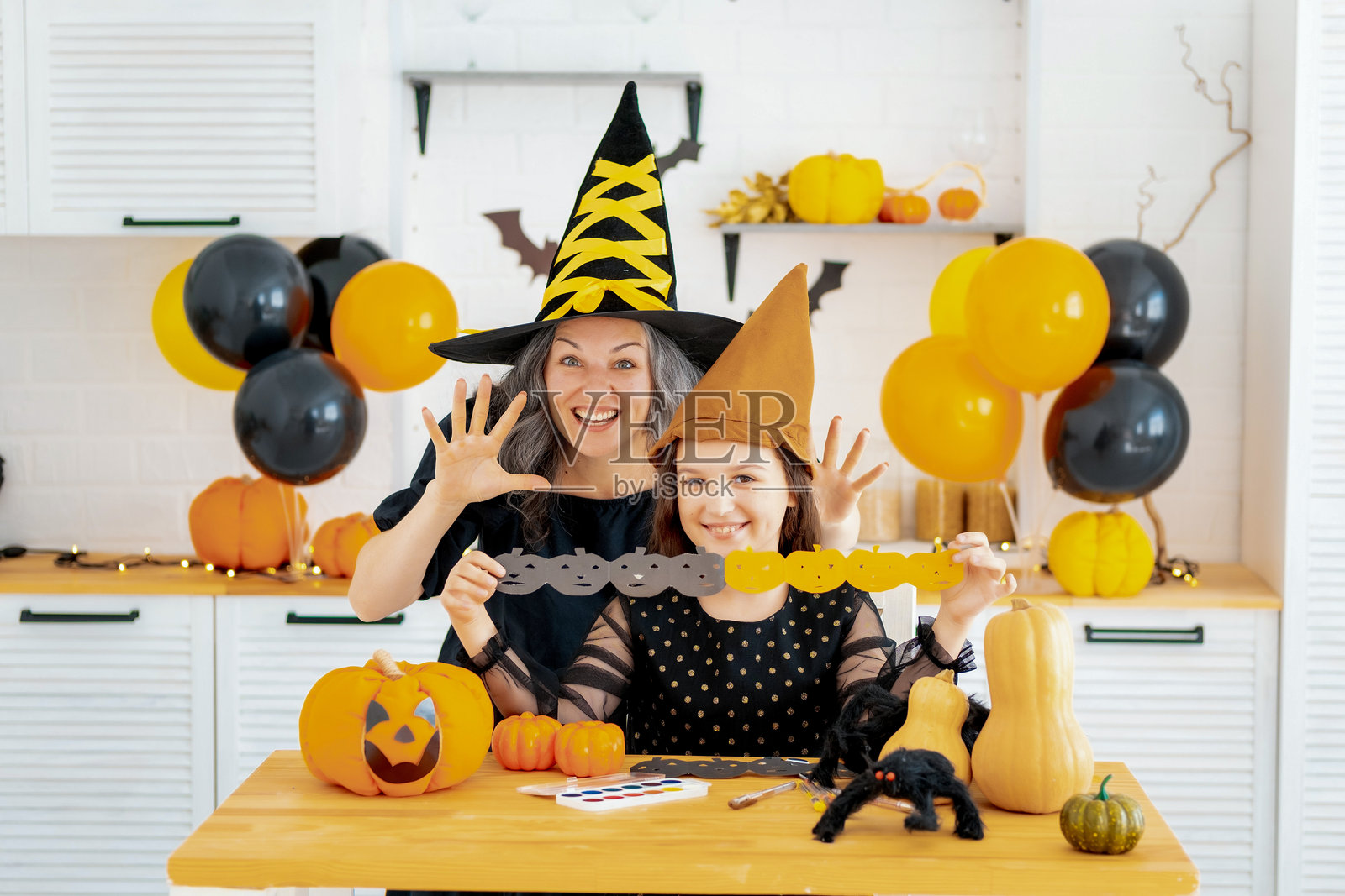 万圣节，一个穿着女巫服装的孩子和母亲正在为万圣节做准备，互相吓唬，拥抱并欢庆，祝贺彼此节日快乐，万圣节快乐。照片摄影图片