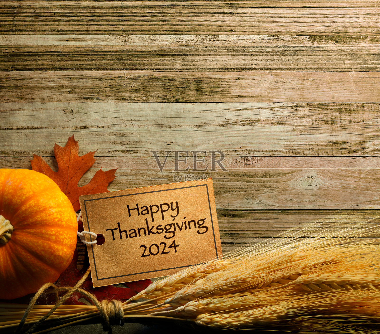 2024年感恩节标签缠绕在麦秆上，放在风化的木质表面上照片摄影图片