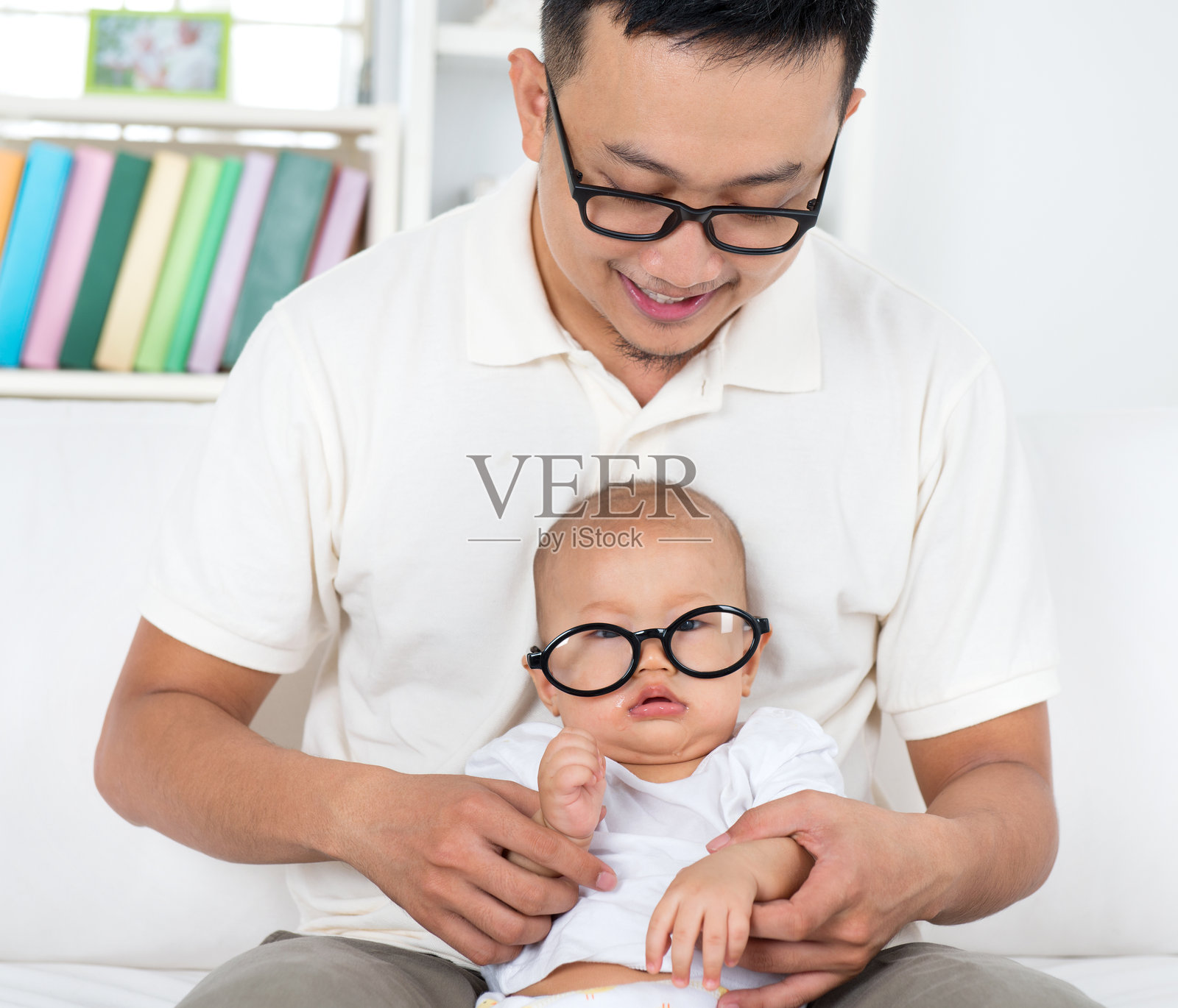 父亲在家沙发上抱着可爱的儿子照片摄影图片