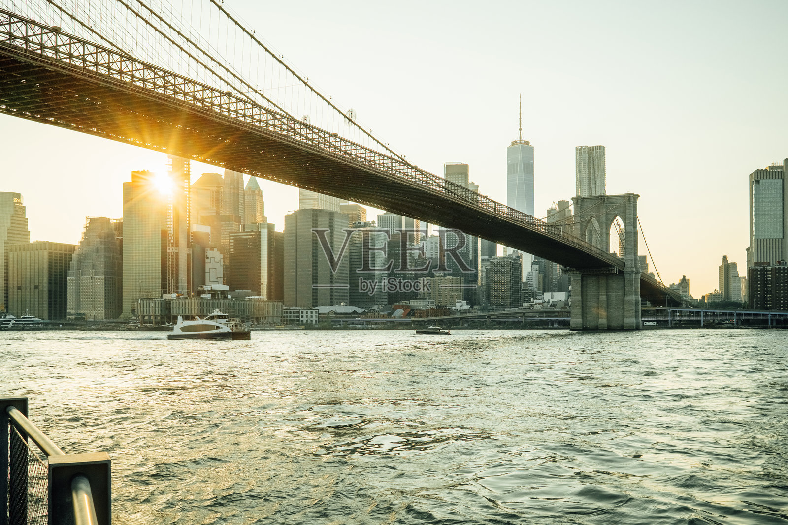 夕阳下布鲁克林大桥下的阳光，曼哈顿天际线在背景中。照片摄影图片