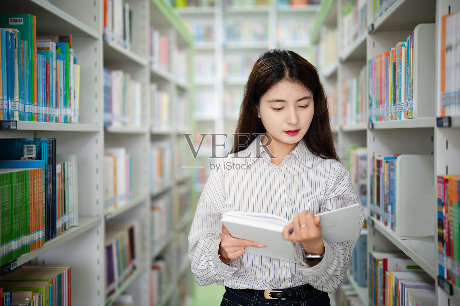 成年女性大学生在公共图书馆借书照片摄影图片