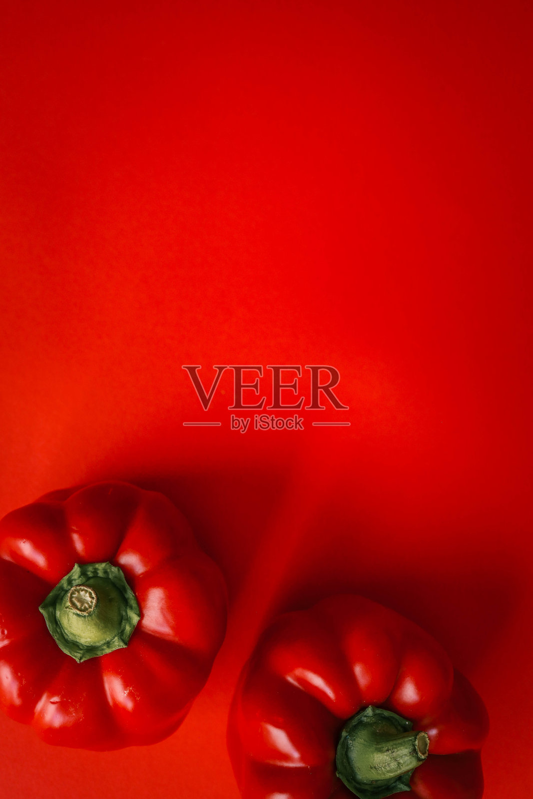 极简主义图像，两个鲜艳的红椒放置在相配的红色背景上照片摄影图片