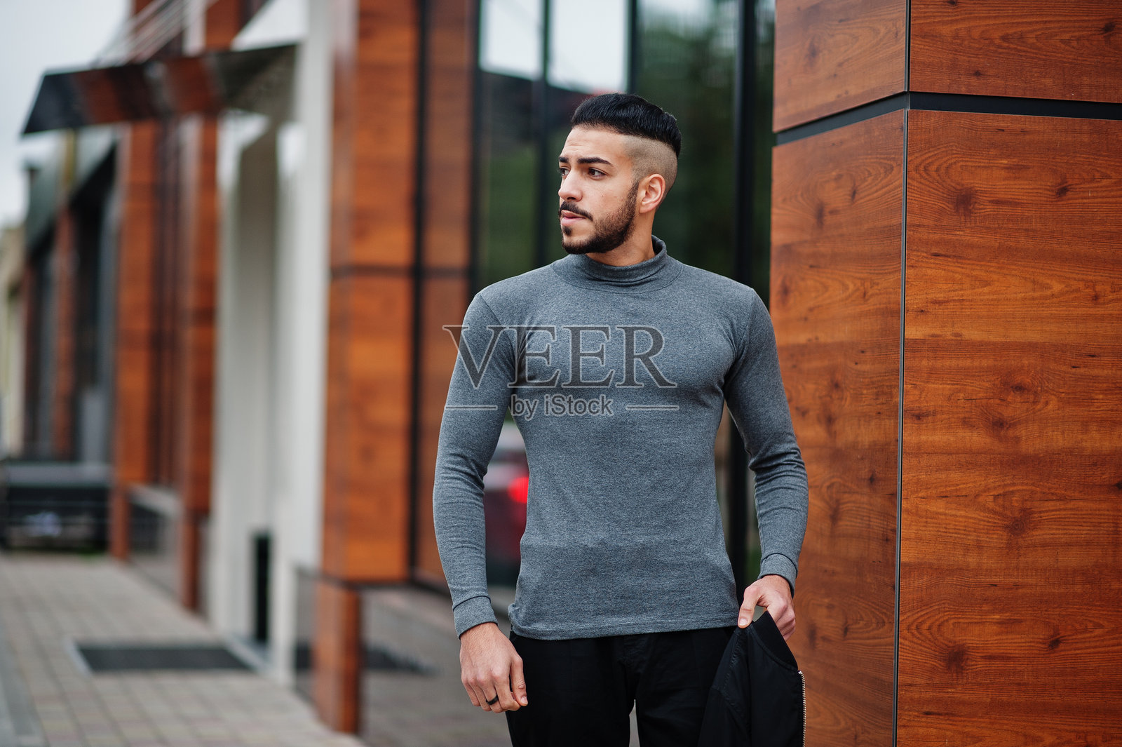 戴灰色高领毛衣和黑色夹克的时尚阿拉伯胡须男人肖像照片摄影图片