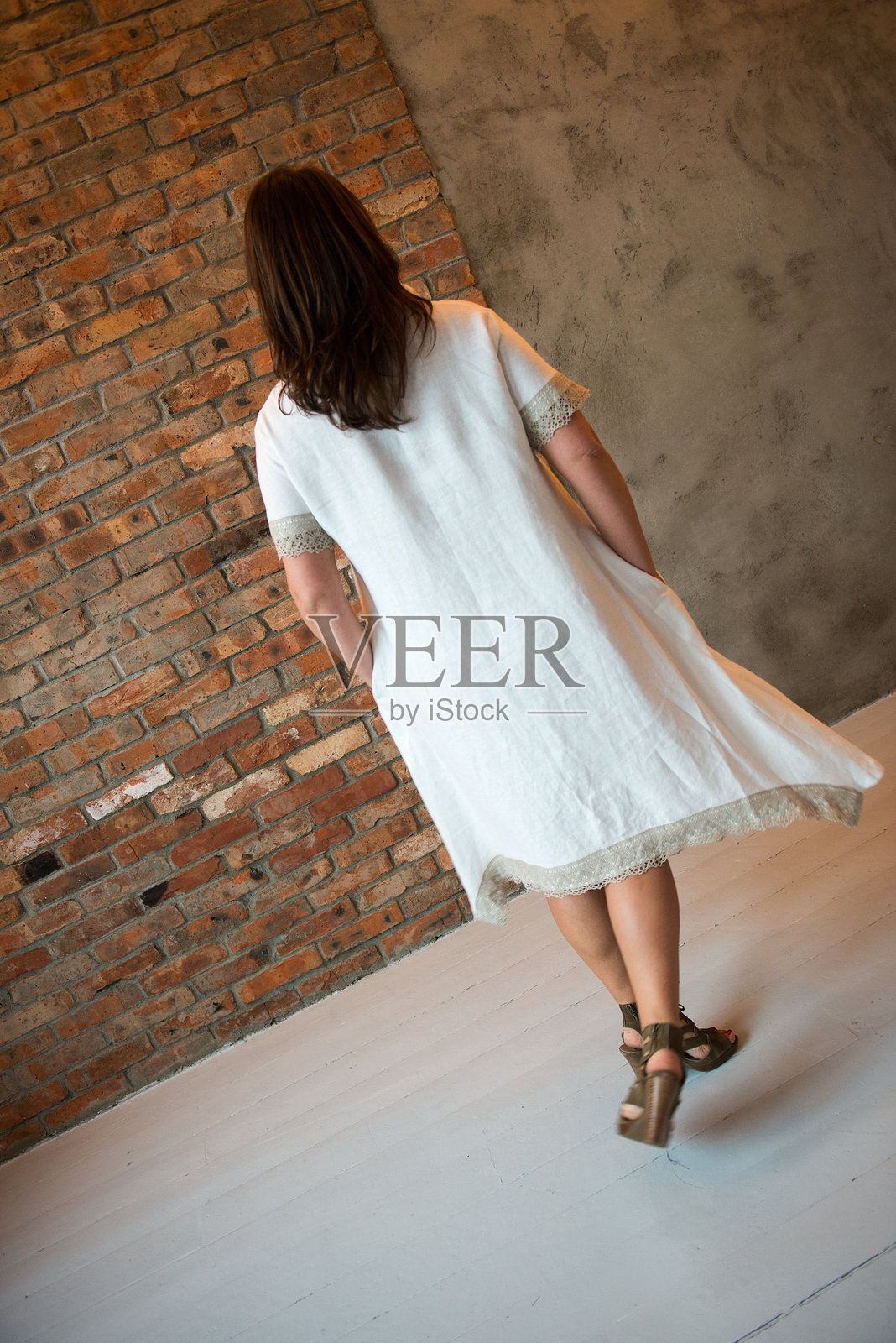 女人全身站立在砖墙旁照片摄影图片