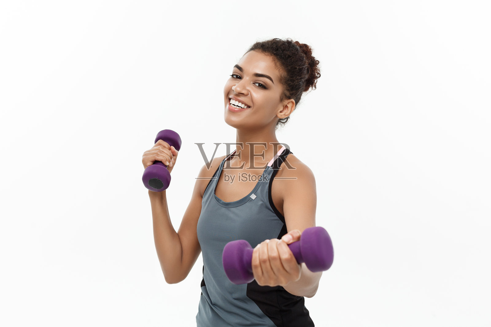 微笑女性在白色背景下举哑铃的肖像照片摄影图片
