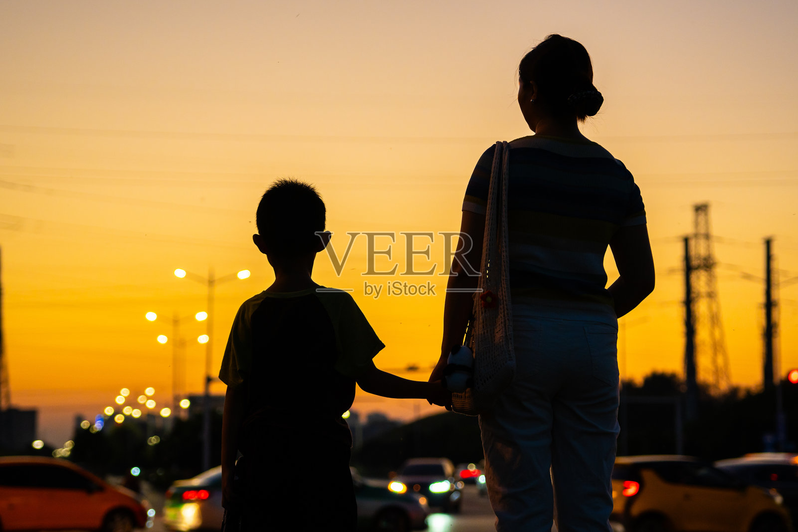 母亲与她的儿子在日落时分的城市街道上站着照片摄影图片