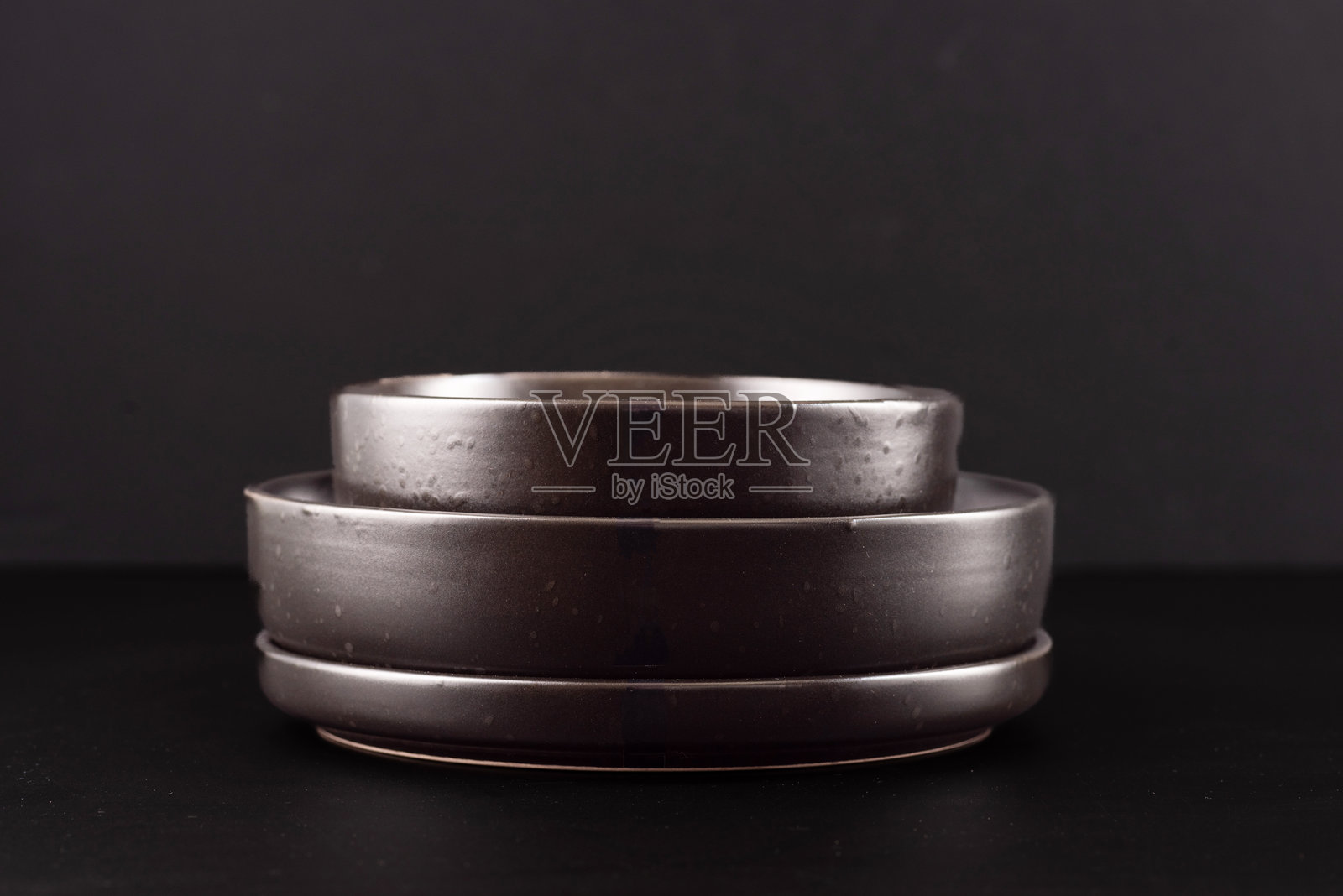 一组黑色盘子放在黑色背景上。黑色陶土餐具。照片摄影图片