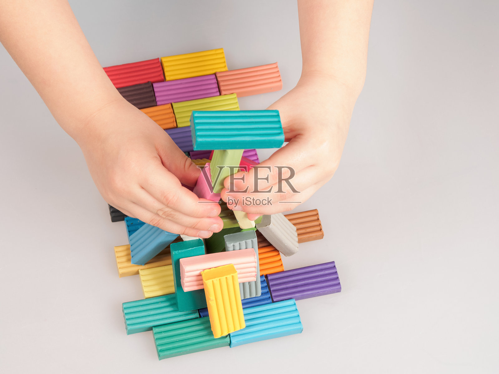 孩子们热情地玩着橡皮泥，塑造出色彩鲜艳的形状，发展创造力和精细运动技能。照片摄影图片