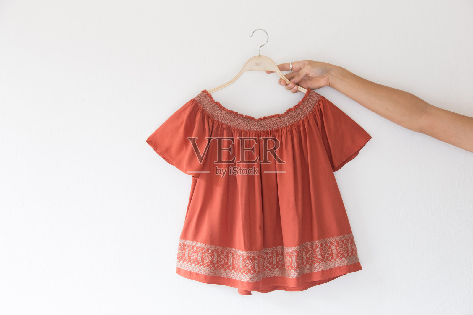 女人的手握着挂在墙上的上衣照片摄影图片