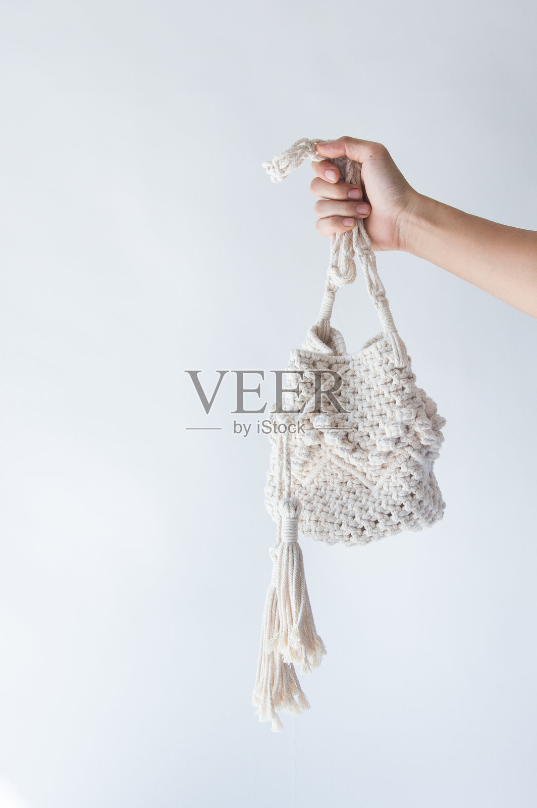 女人手持包袋，背景为白色。照片摄影图片