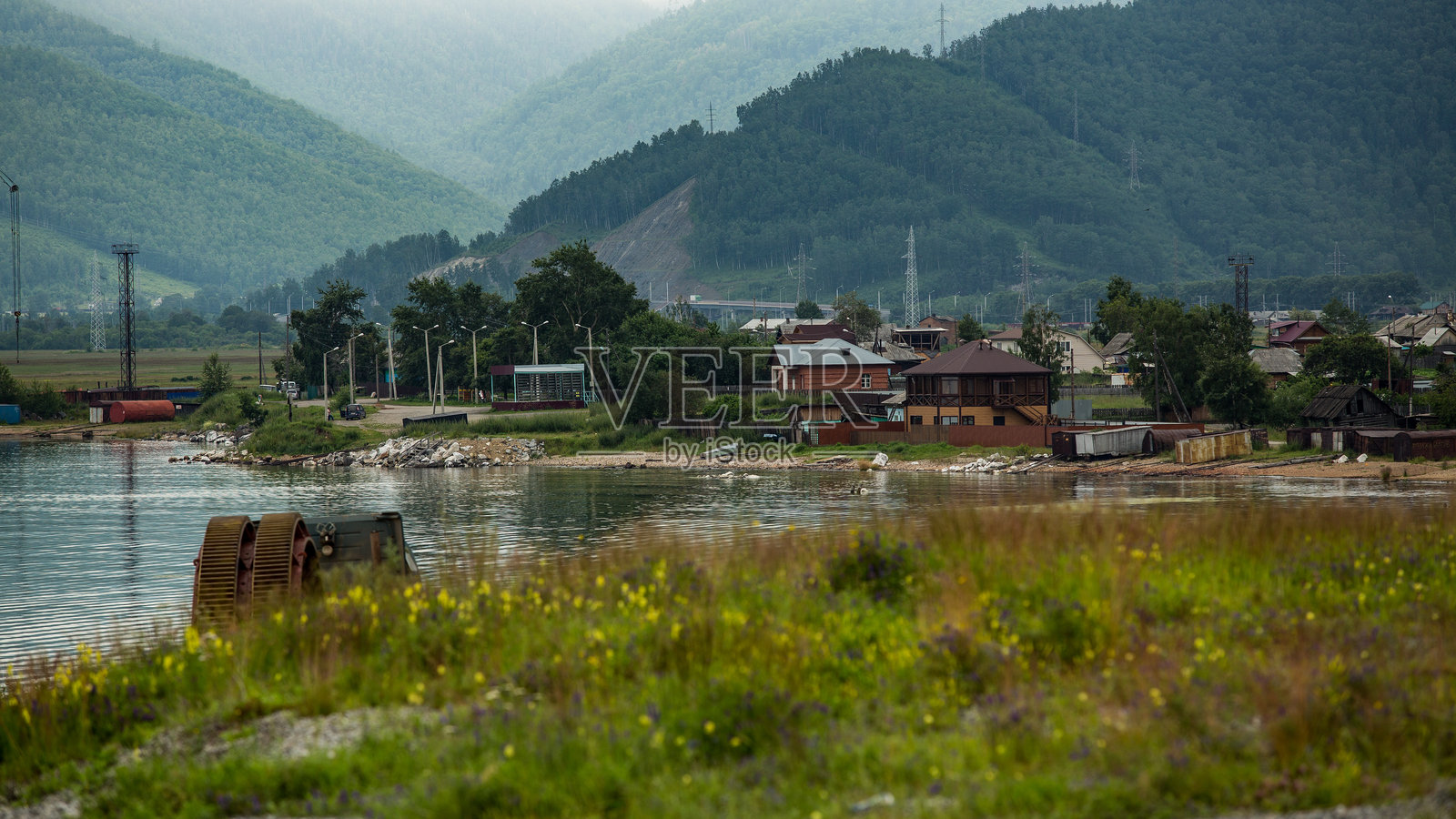 一个小镇坐落在湖边，背景是群山。照片摄影图片