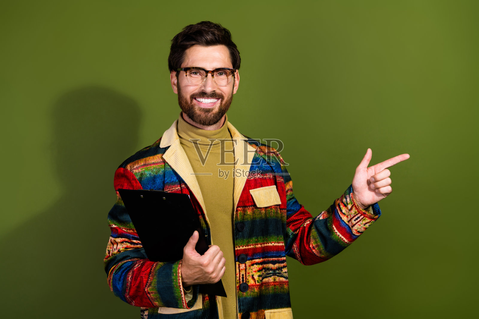 一位吸引人的有胡子的成功男士，穿着时尚的衣服，手持文件，背景为卡其色，空旷的空间。照片摄影图片