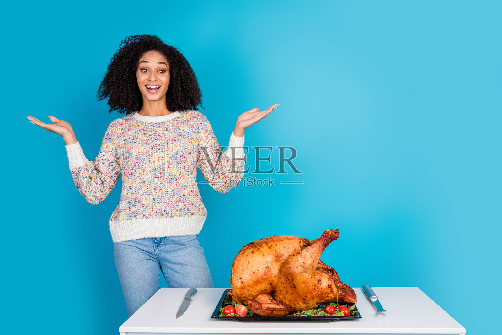 吸引人的年轻女性在蓝色背景下兴奋地庆祝感恩节晚餐，手中拿着火鸡的照片肖像照片摄影图片