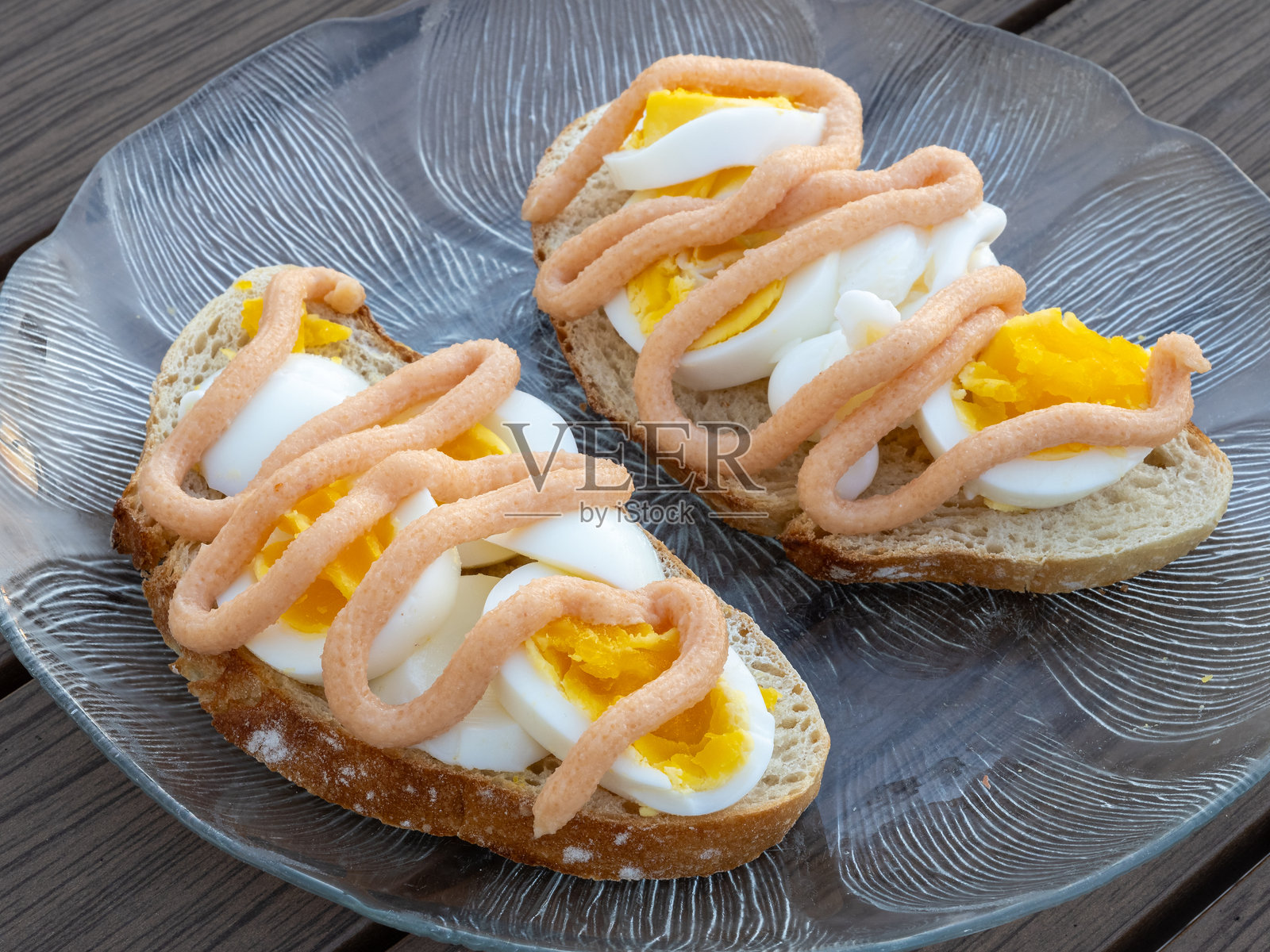 侧面视图的两款传统三明治，夹有切片鸡蛋和瑞典风格的鱼子酱，摆放在玻璃盘上。照片摄影图片