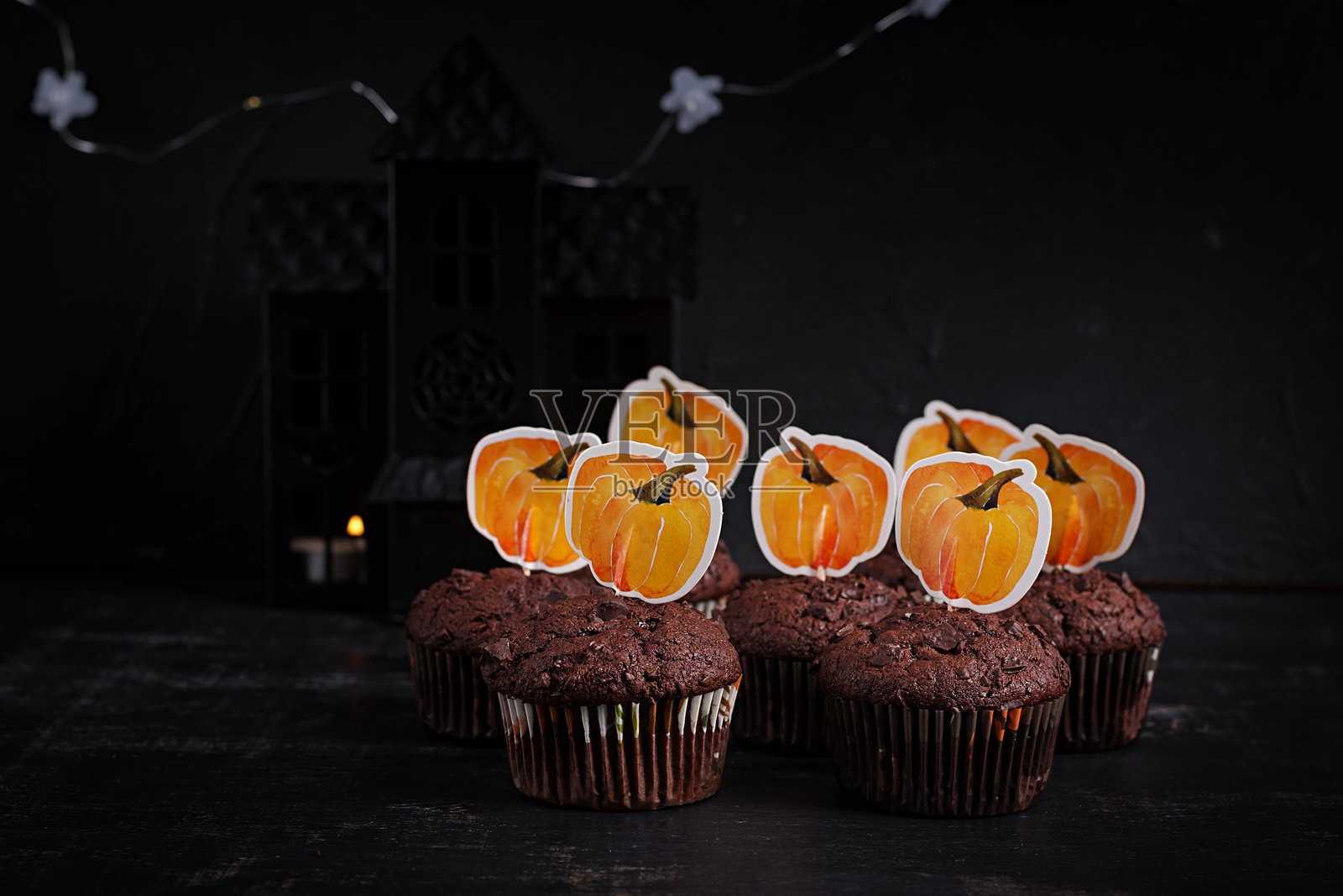 节日气氛的万圣节杯子蛋糕和用搞笑贴纸装饰的甜点。万圣节松饼。巧克力松饼。照片摄影图片