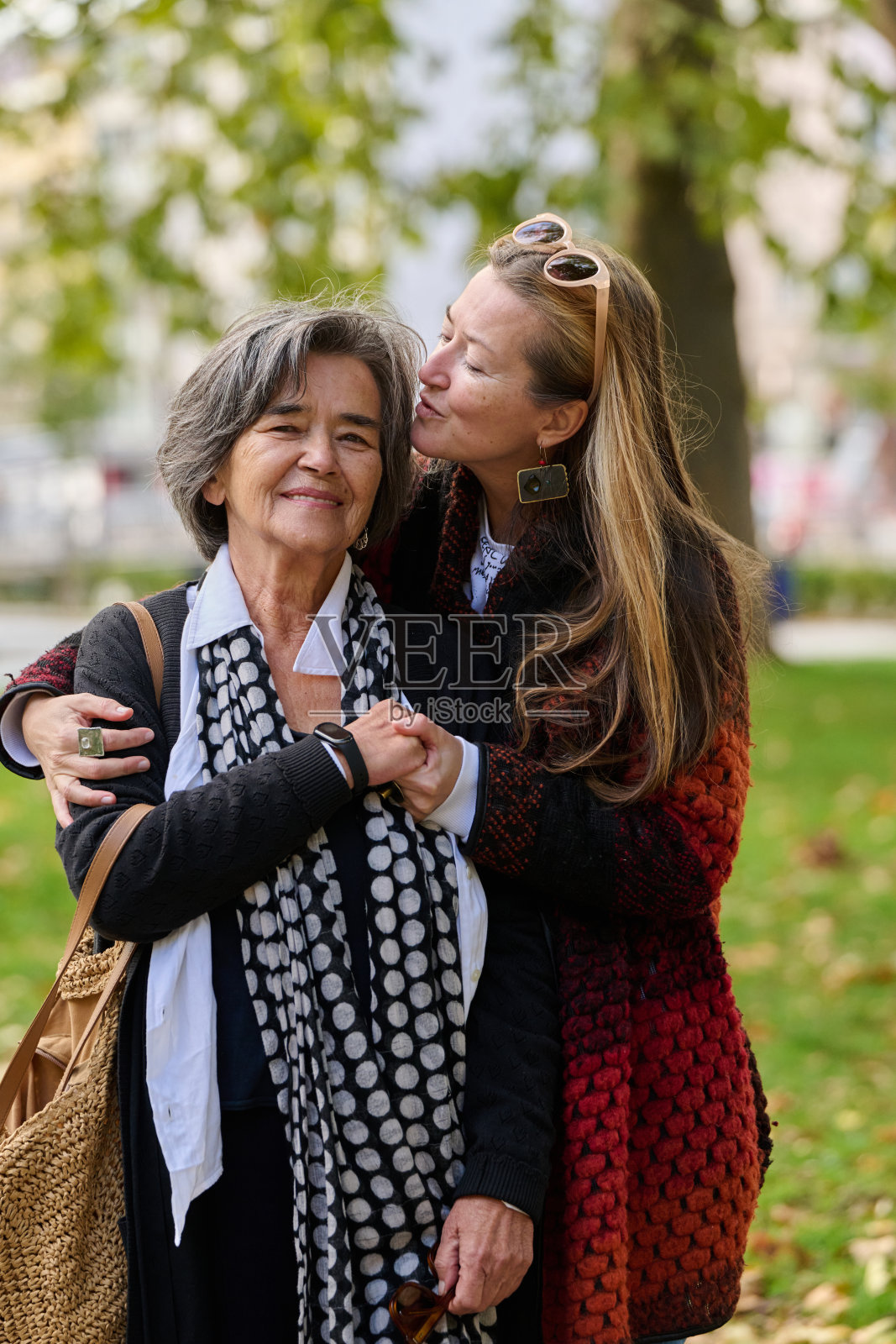 温暖的拥抱：女儿在美丽的秋日里对母亲的支持。照片摄影图片