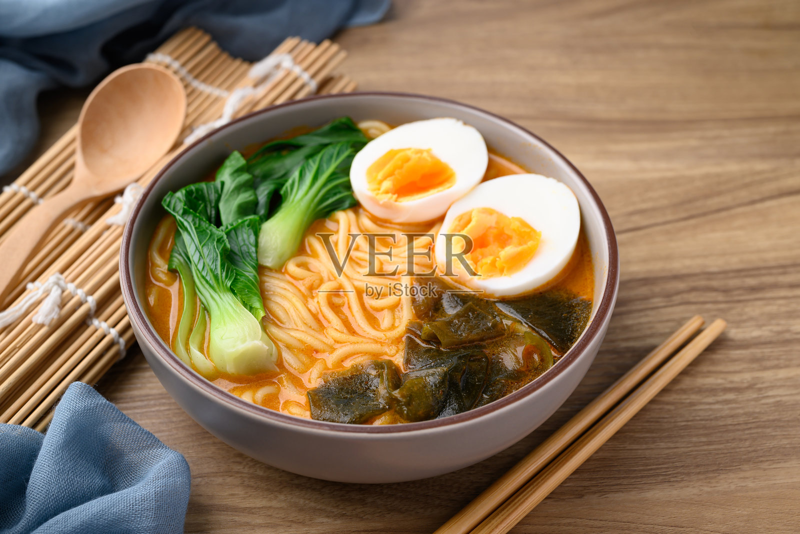 碗里盛着辣味面条汤，配有鸡蛋、海带和小白菜，亚洲风味面条。照片摄影图片