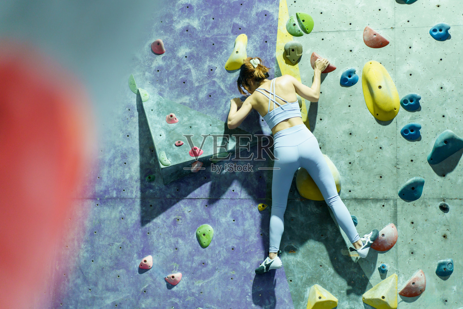 亚洲女运动员在室内攀岩墙上练习。照片摄影图片