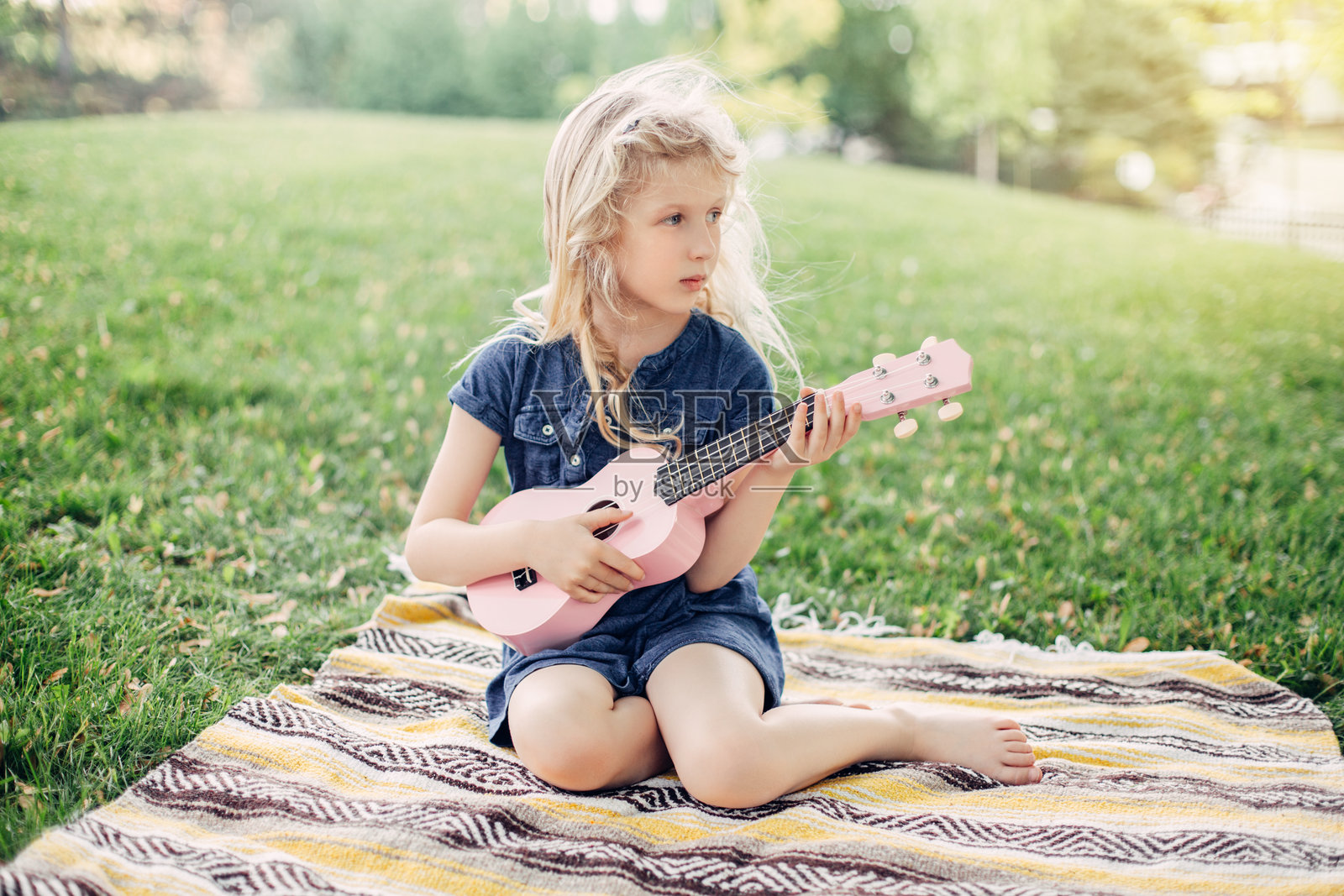可爱的金发女孩在户外玩粉色吉他玩具。孩子在演奏音乐并唱歌。照片摄影图片