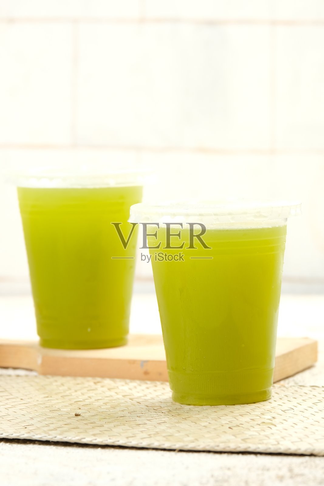 清澈塑料杯中盛着清爽的甘蔗汁，泡沫丰富。照片摄影图片