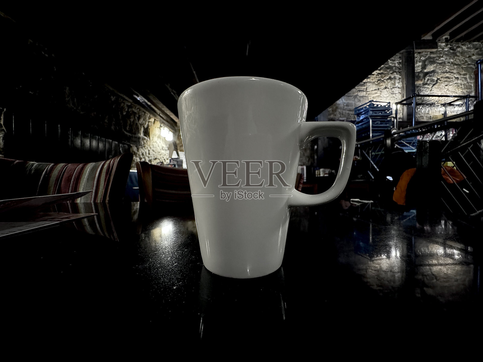 一只干净的白色陶瓷咖啡杯放在昏暗的餐厅桌子上照片摄影图片