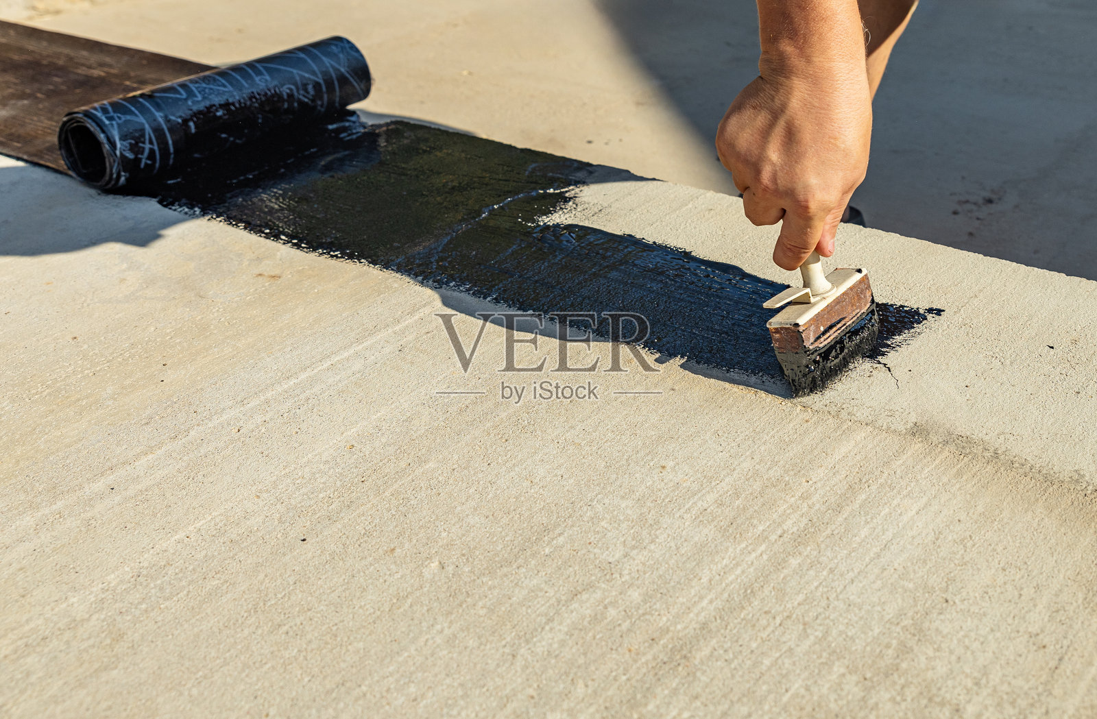 防水地下室和基础的施工技术。地下室混凝土墙上的绝缘材料。使用喷涂沥青和卷材防水材料进行房屋基础防水。照片摄影图片