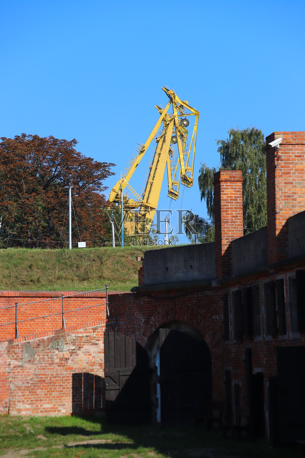 现代起重机矗立在古老的堡垒历史建筑后面照片摄影图片
