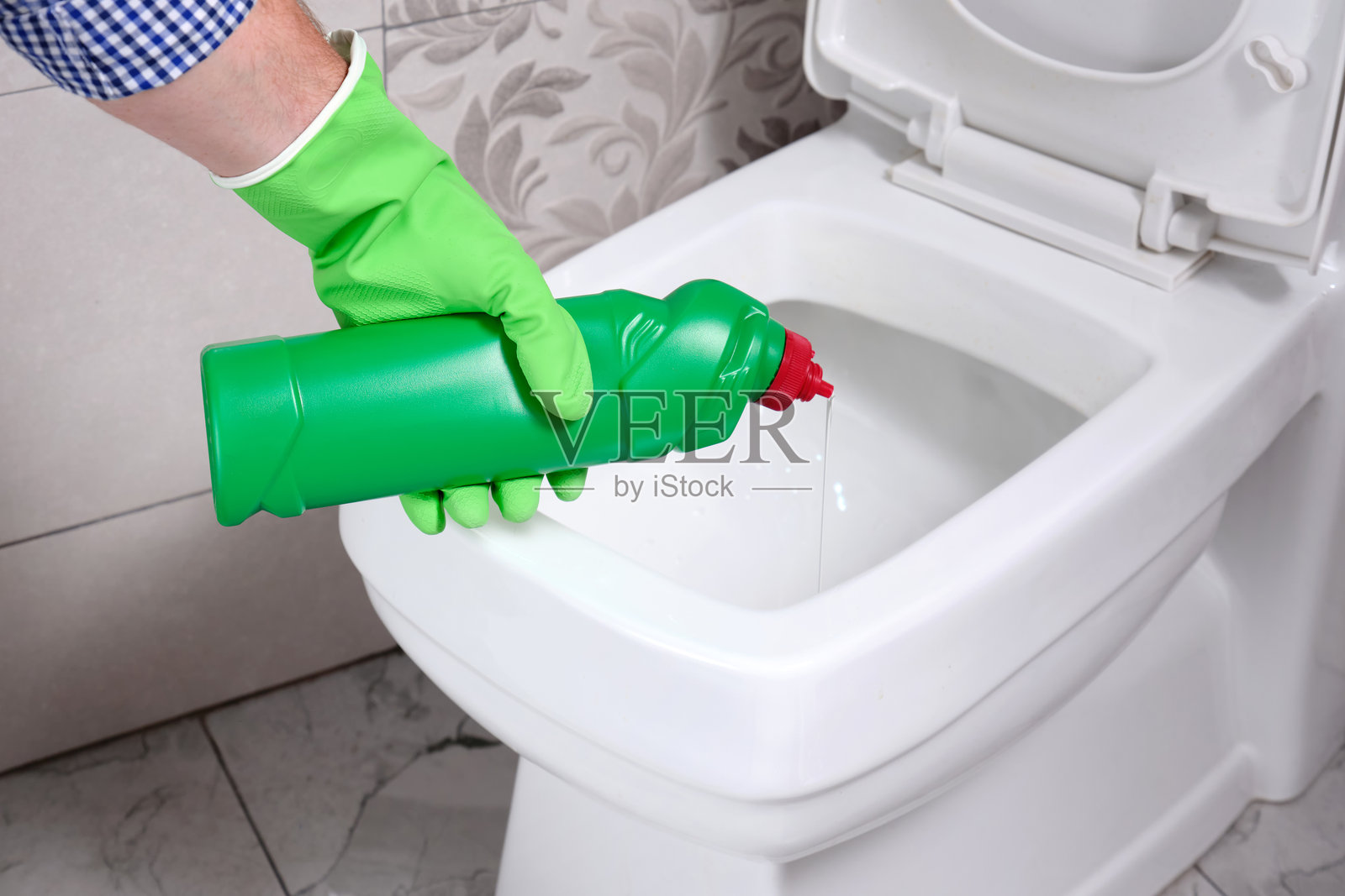 一名男子在公寓的厕所里从瓶子里倒入消毒剂。照片摄影图片