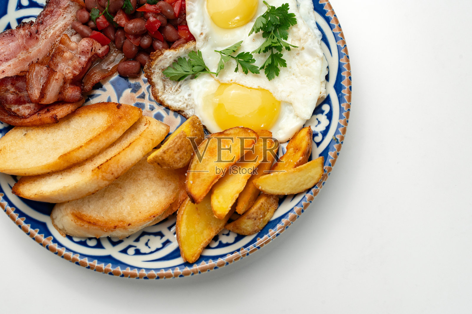 美味的早餐盘，包含鸡蛋、豆类、培根和土豆角，盛放在精美的盘子上照片摄影图片