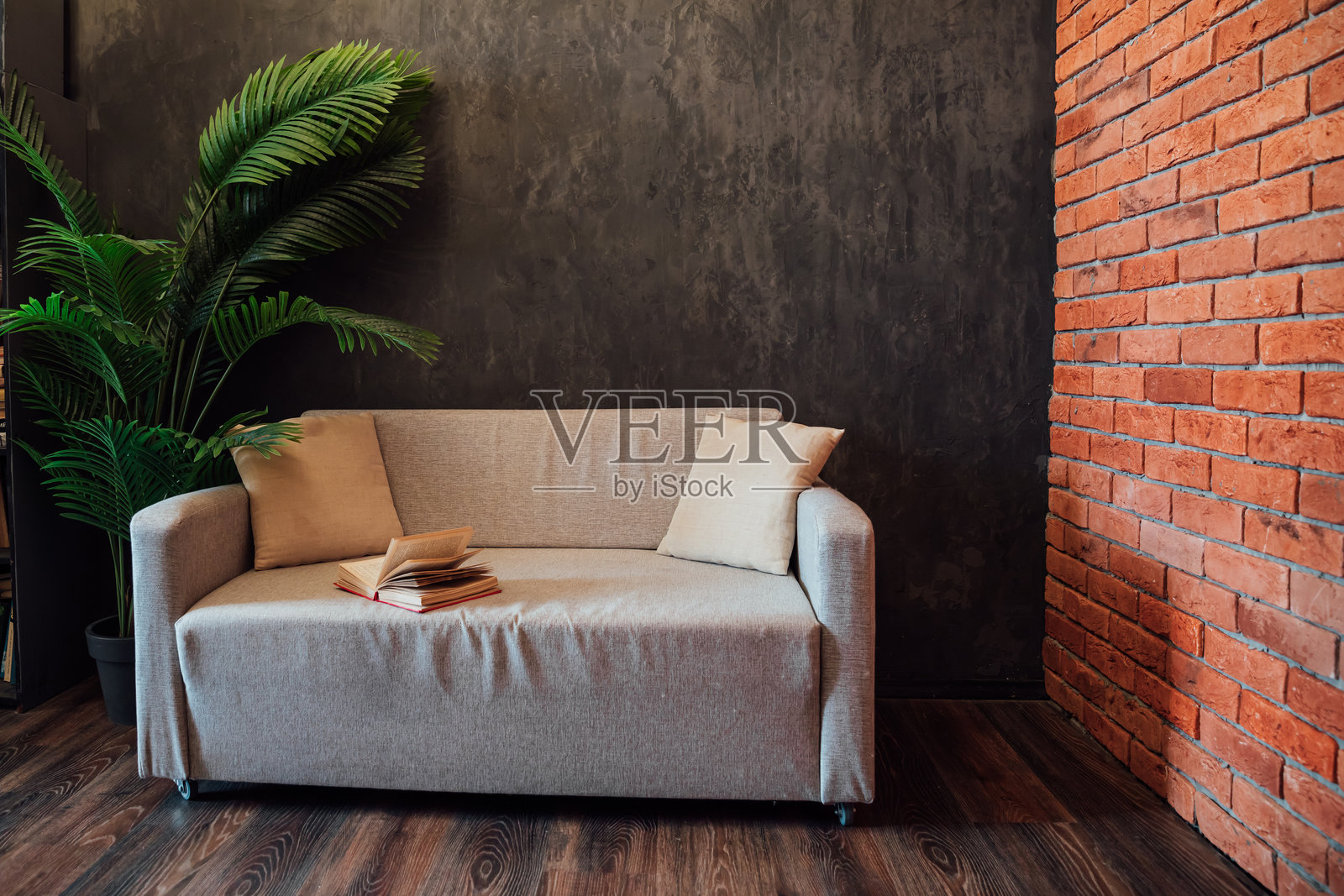 灰色办公室沙发旁的书与灰色砖砌阁楼墙照片摄影图片