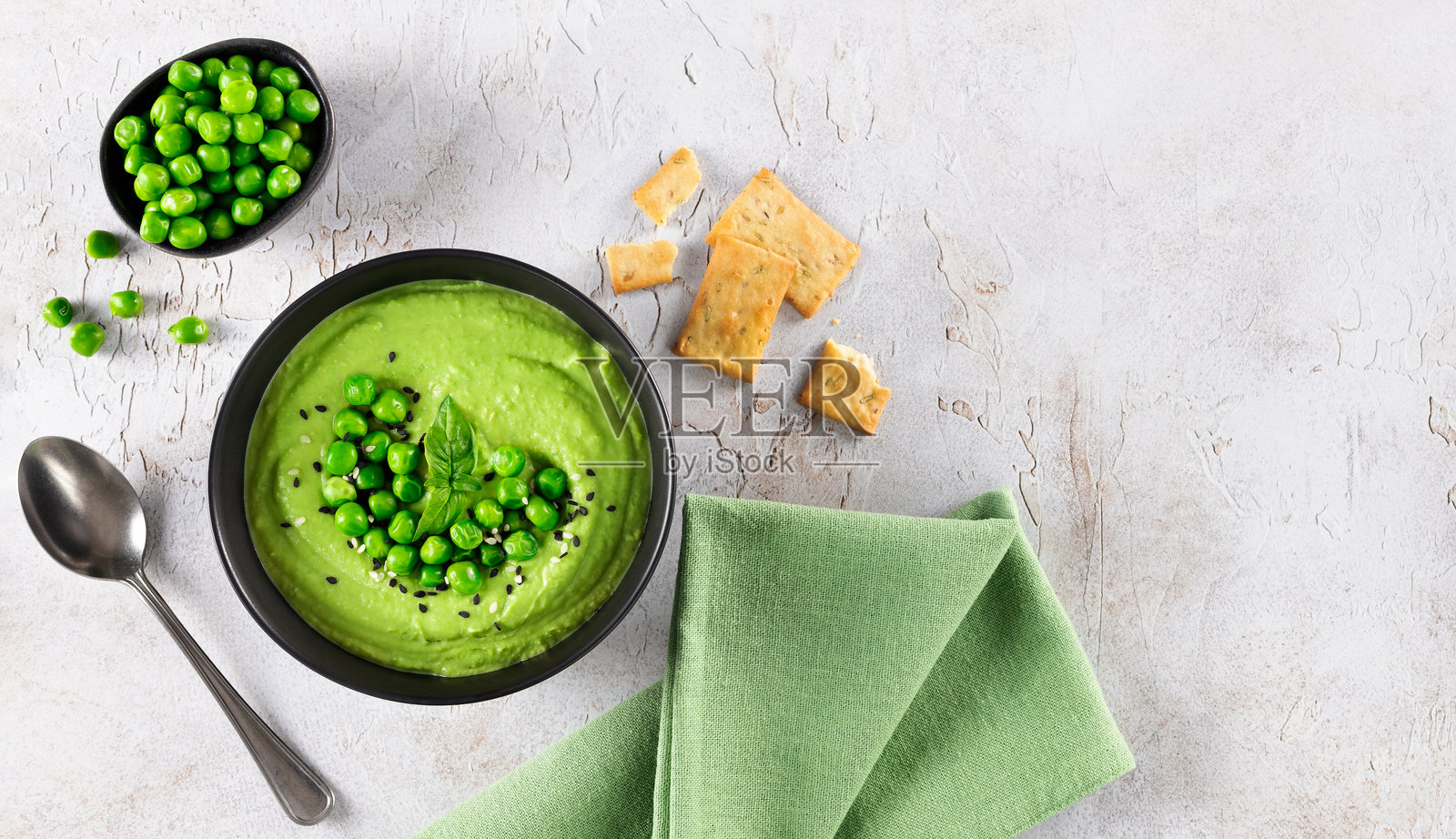 灰色桌子上的搭配饼干的绿色豌豆奶油汤，俯视照片摄影图片
