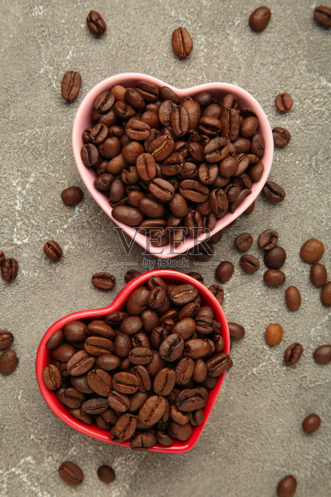 灰色混凝土背景上的心形碗中的咖啡豆。俯视图照片摄影图片