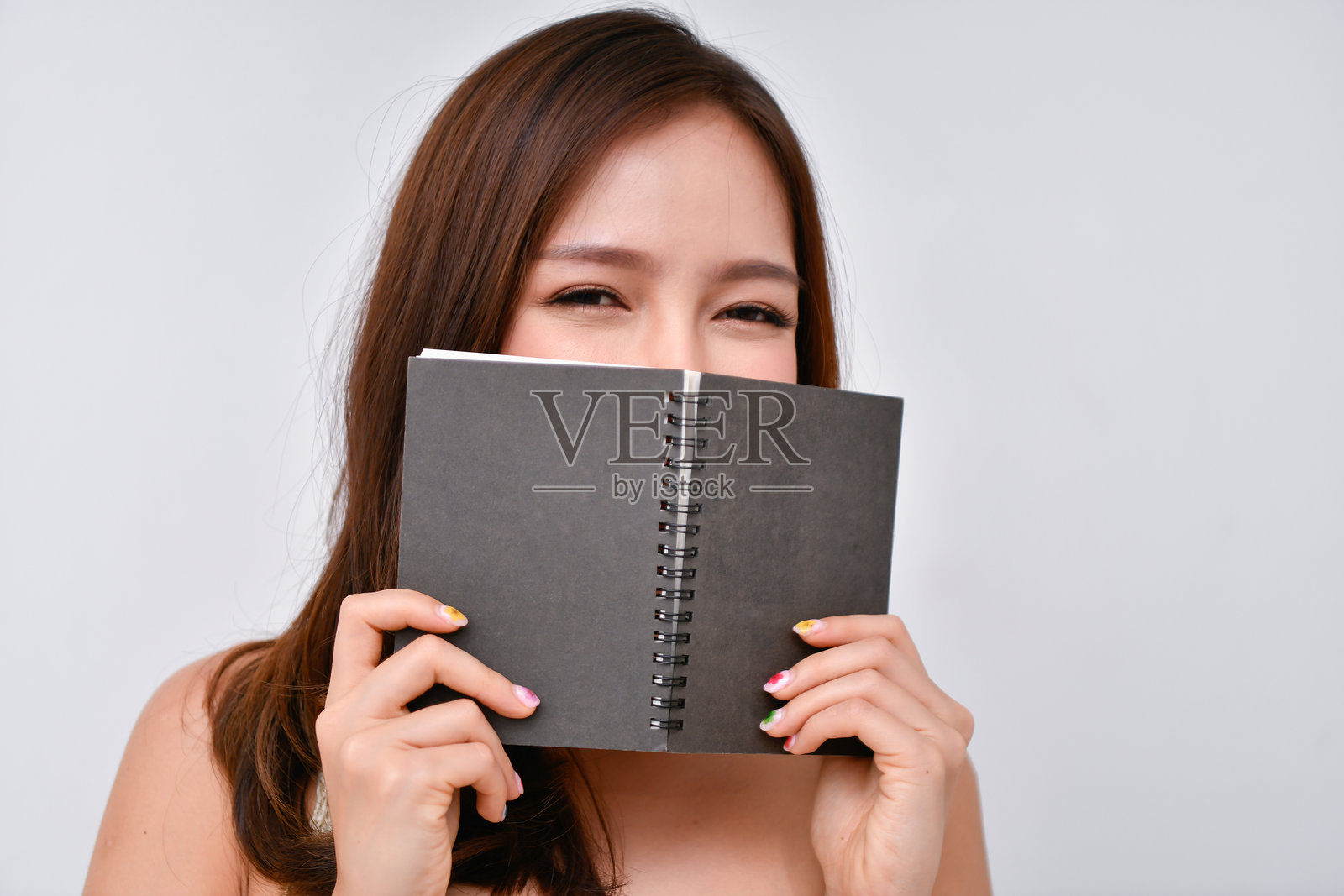 年轻女性手持书籍的肖像，背景为白色照片摄影图片