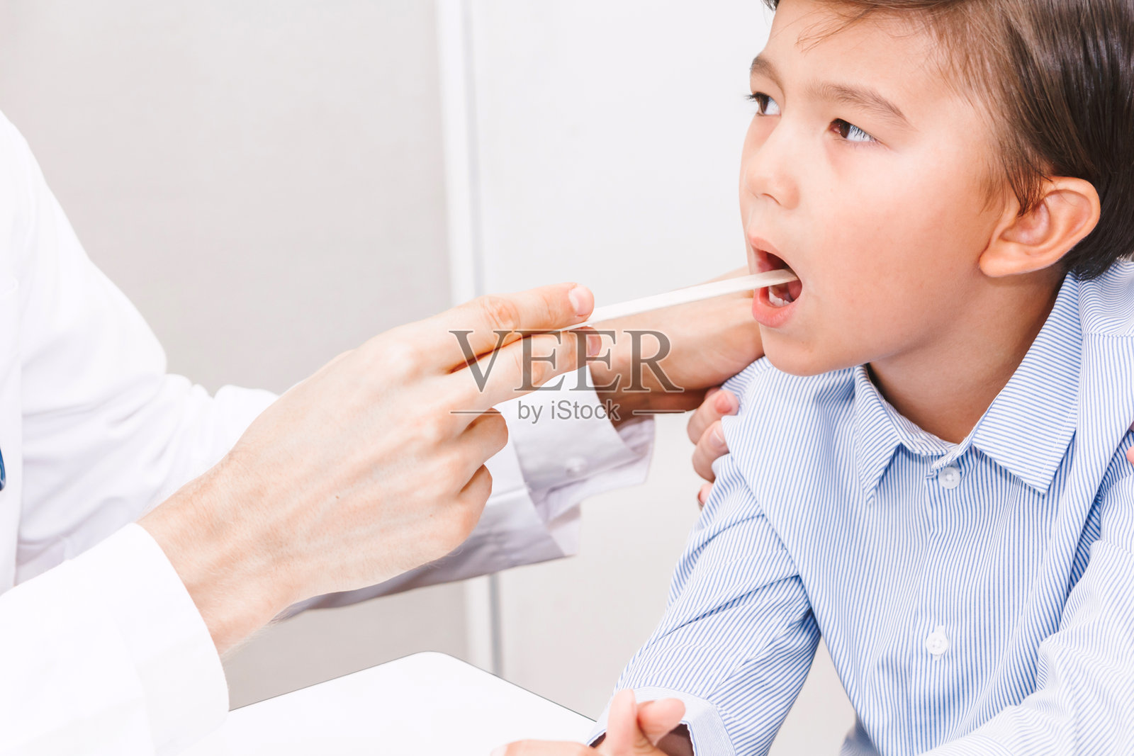 医生在医院检查男孩口腔的手部特写照片摄影图片