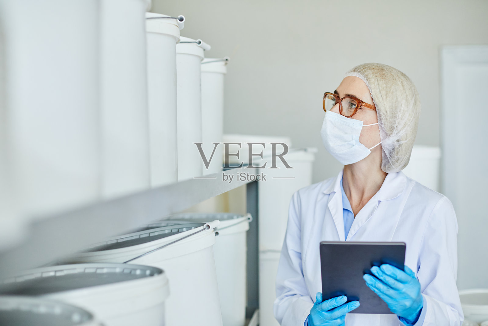 女性技术人员在制药厂的仓库中检查容器照片摄影图片