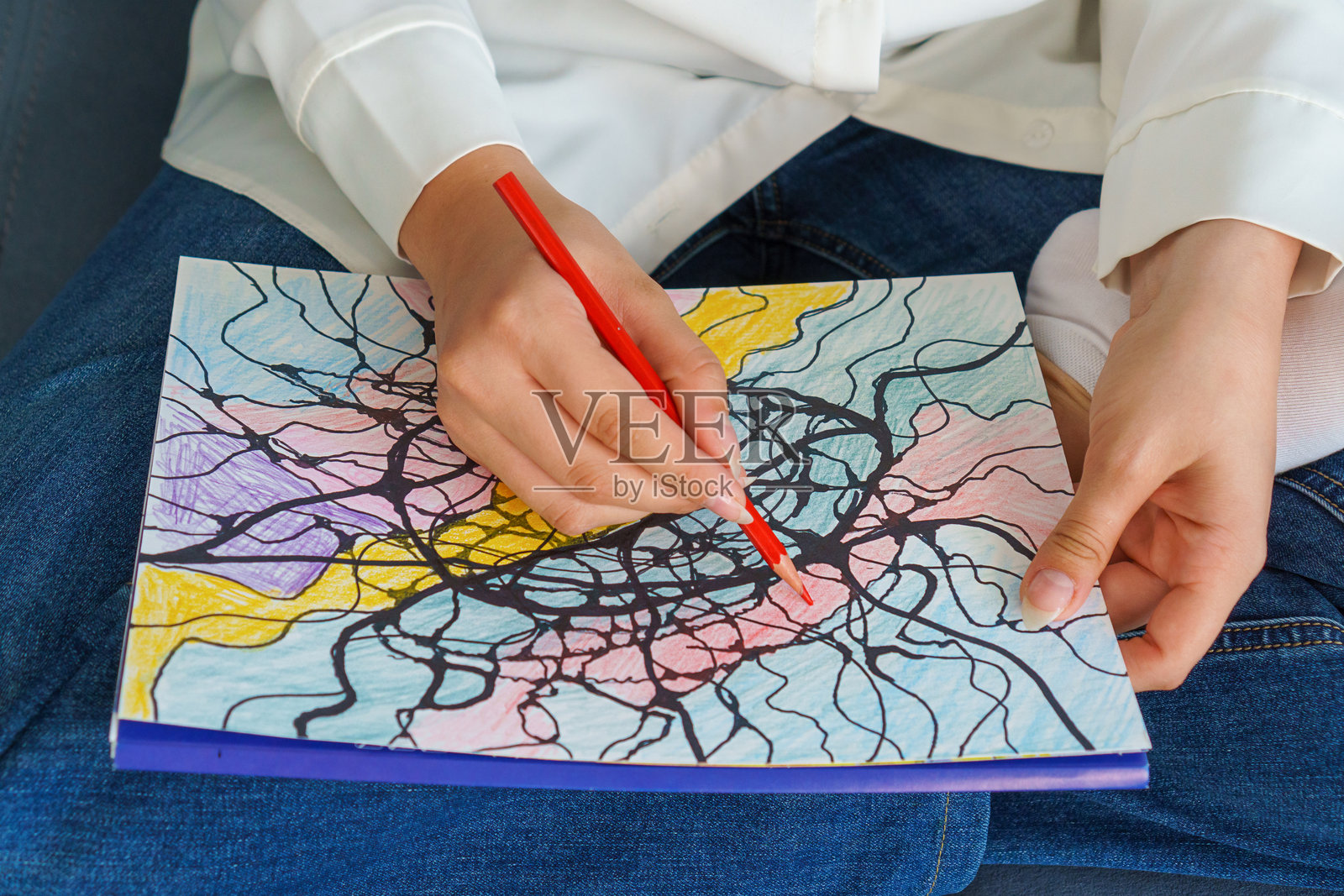 明亮多彩的神经图形绘画特写。女孩坐在沙发上在家中绘画。冥想，寻找潜意识中的答案。神经图形绘画。照片摄影图片