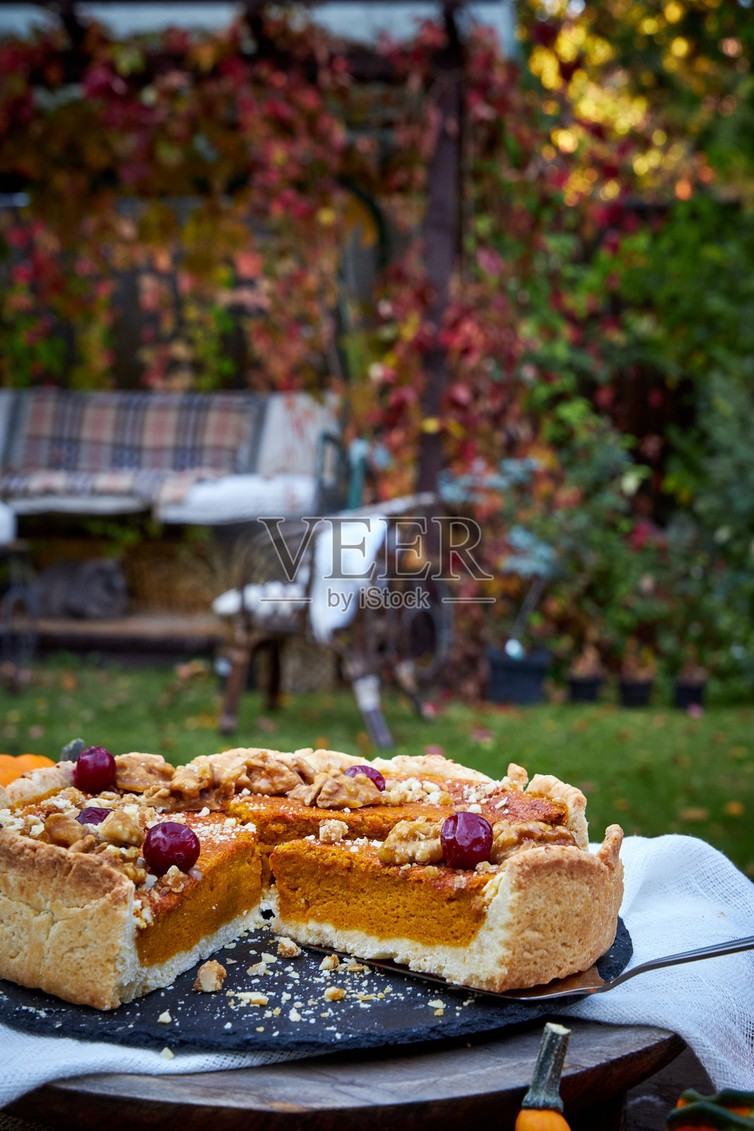 黑色托盘上的南瓜派俯视图，放置在木桌上，周围有南瓜和秋天的树叶。照片摄影图片