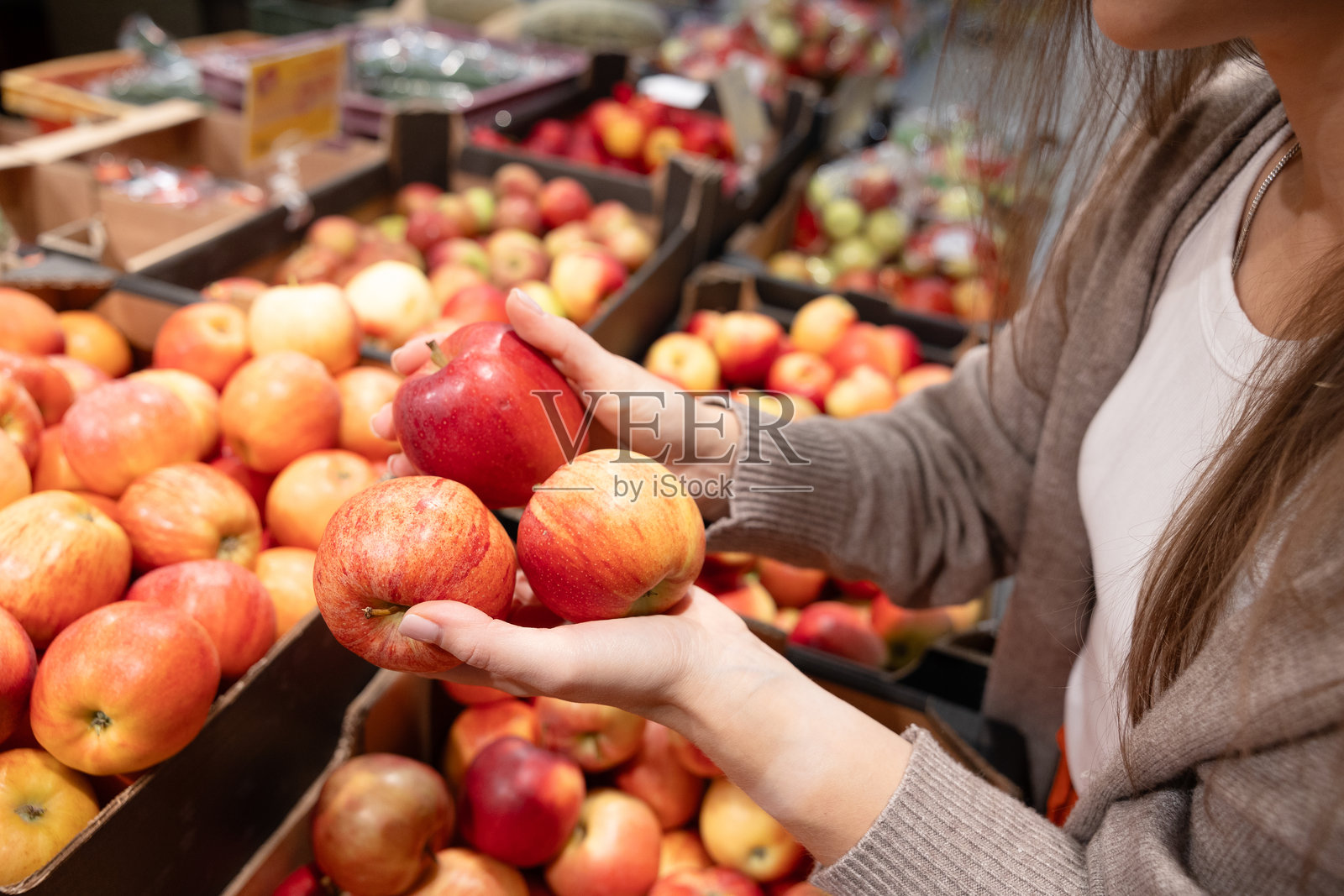 超近距离拍摄手握新鲜苹果的画面，展示在杂货店内选择有机农产品、健康饮食和购买新鲜食材的概念。照片摄影图片
