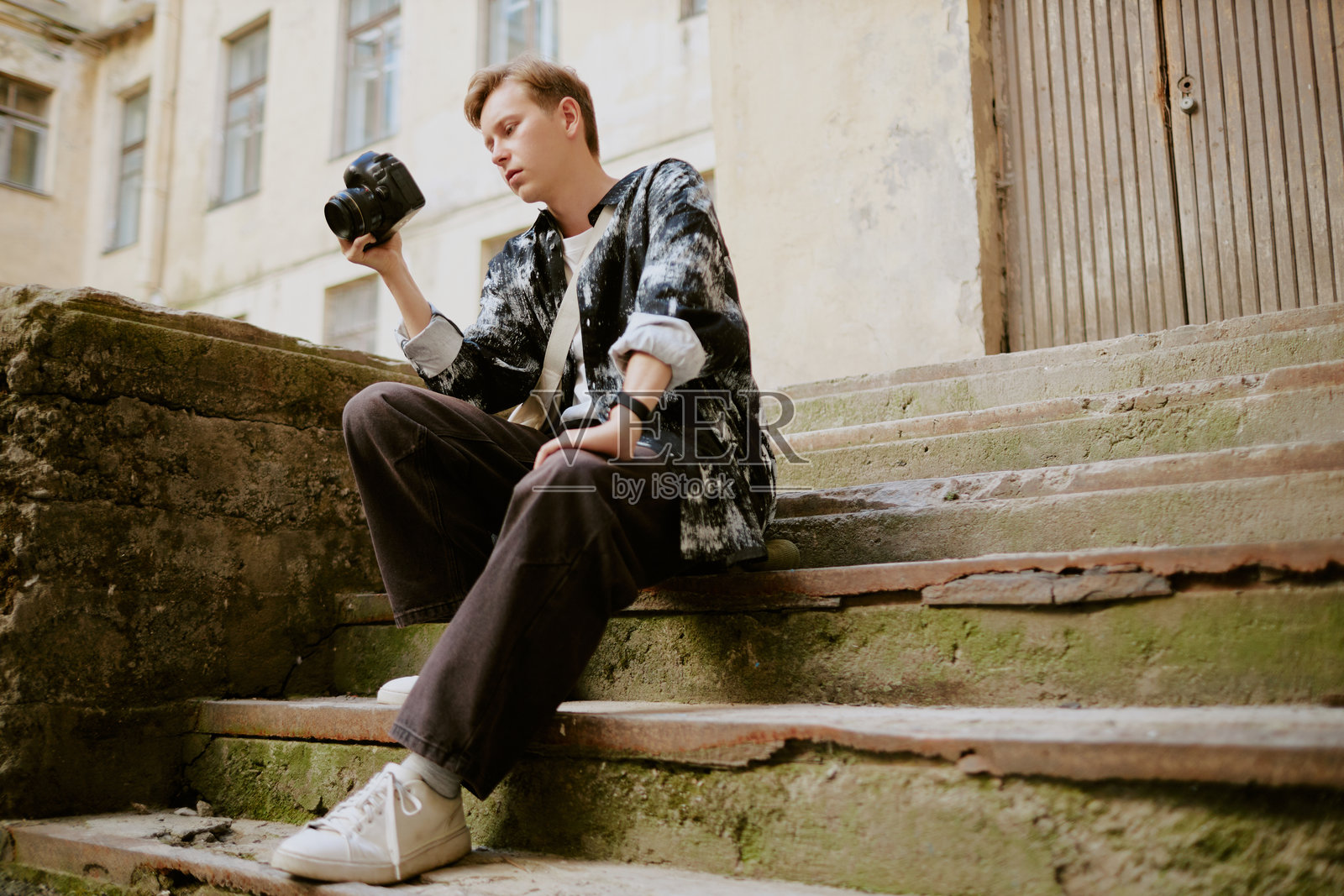 年轻男子坐在户外台阶上拿着相机照片摄影图片