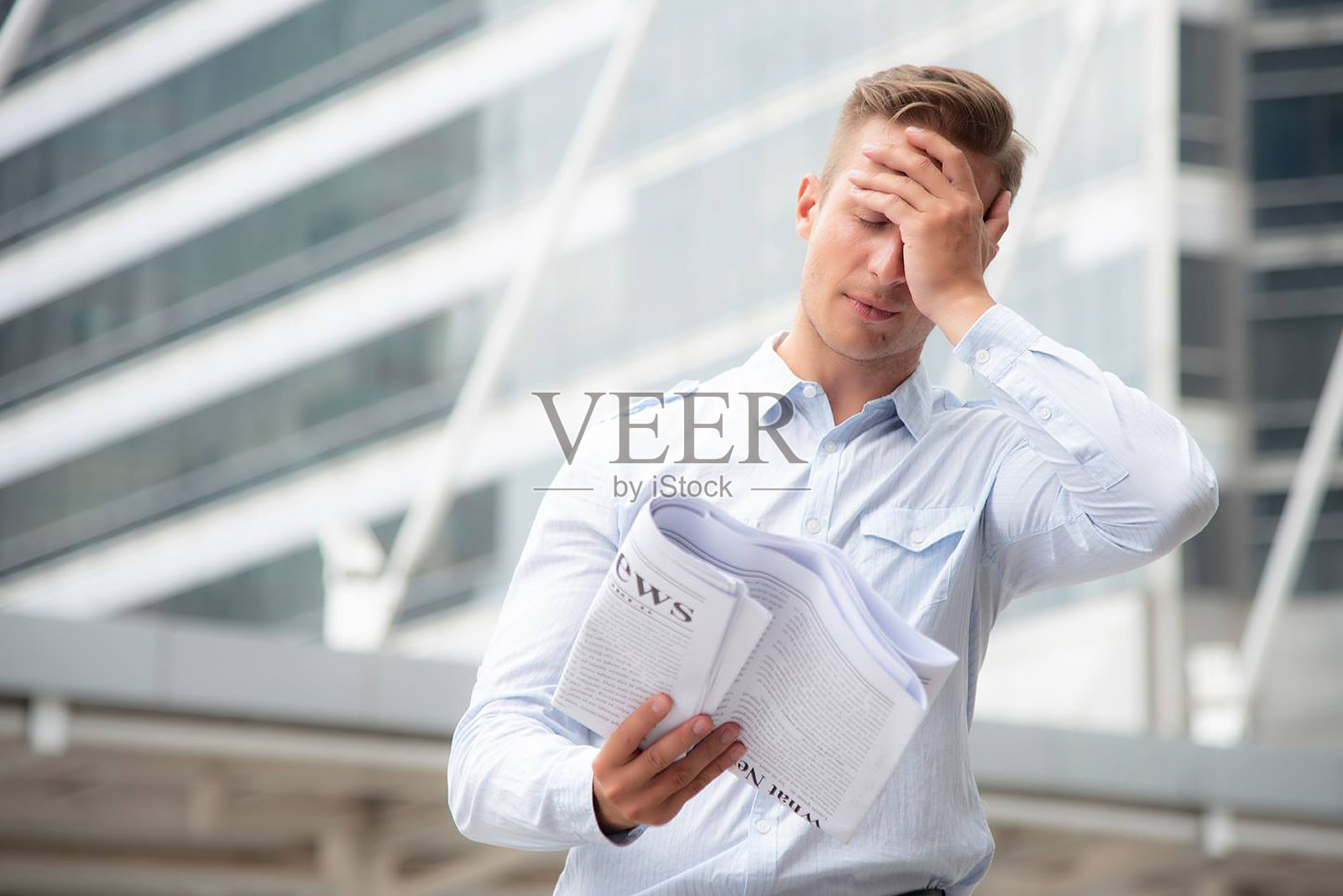 低角度视图的沮丧商人对着建筑物阅读报纸照片摄影图片