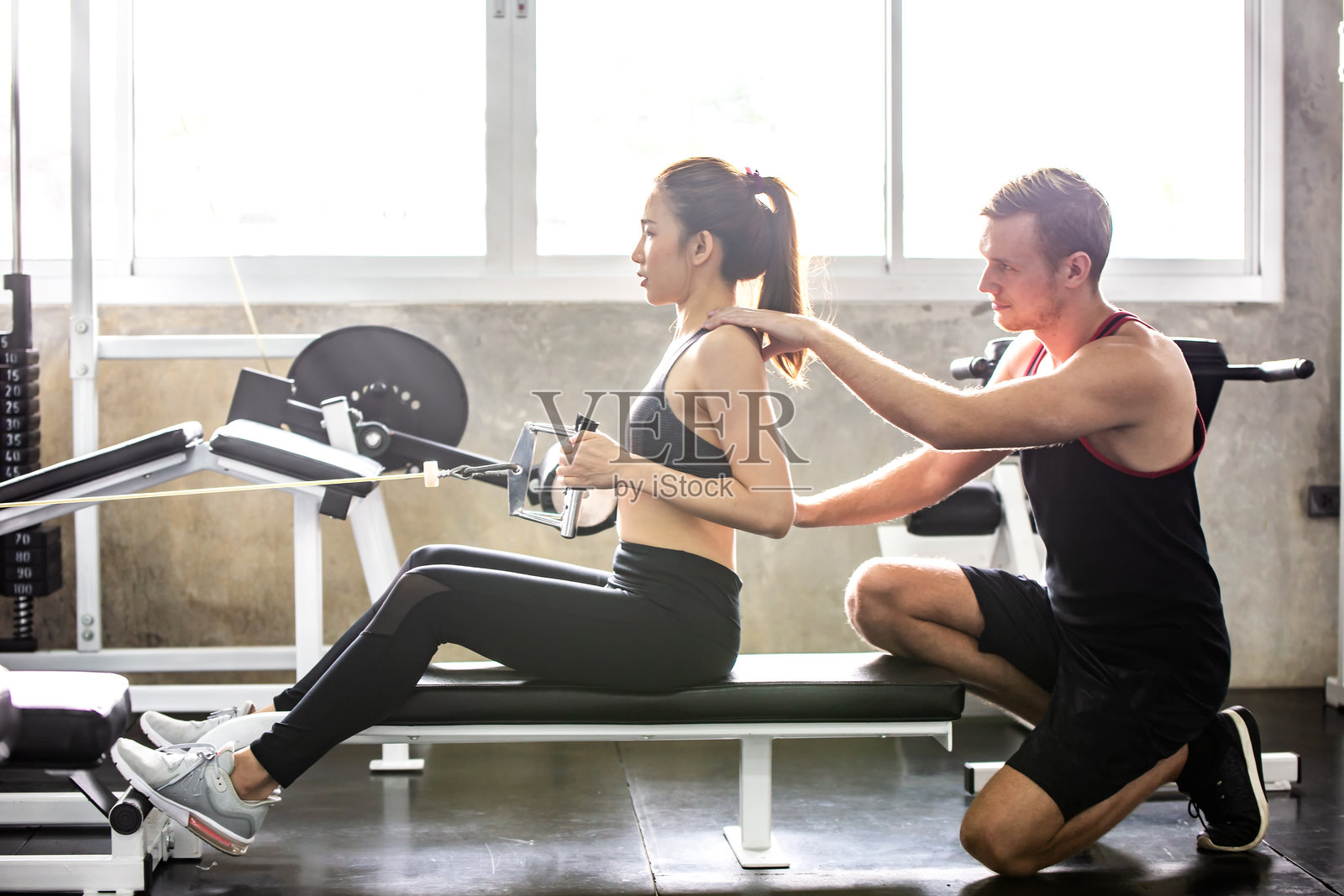朋友在健身房帮助女性锻炼照片摄影图片