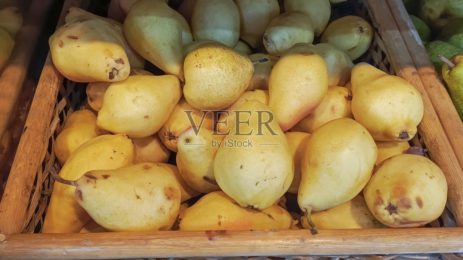 超市木箱中的成熟黄色梨。新鲜梨在蔬菜水果市场的销售。采摘梨。市场上有许多梨在木箱中出售的概念。有机水果和蔬菜的市场交易。素食食品。照片摄影图片