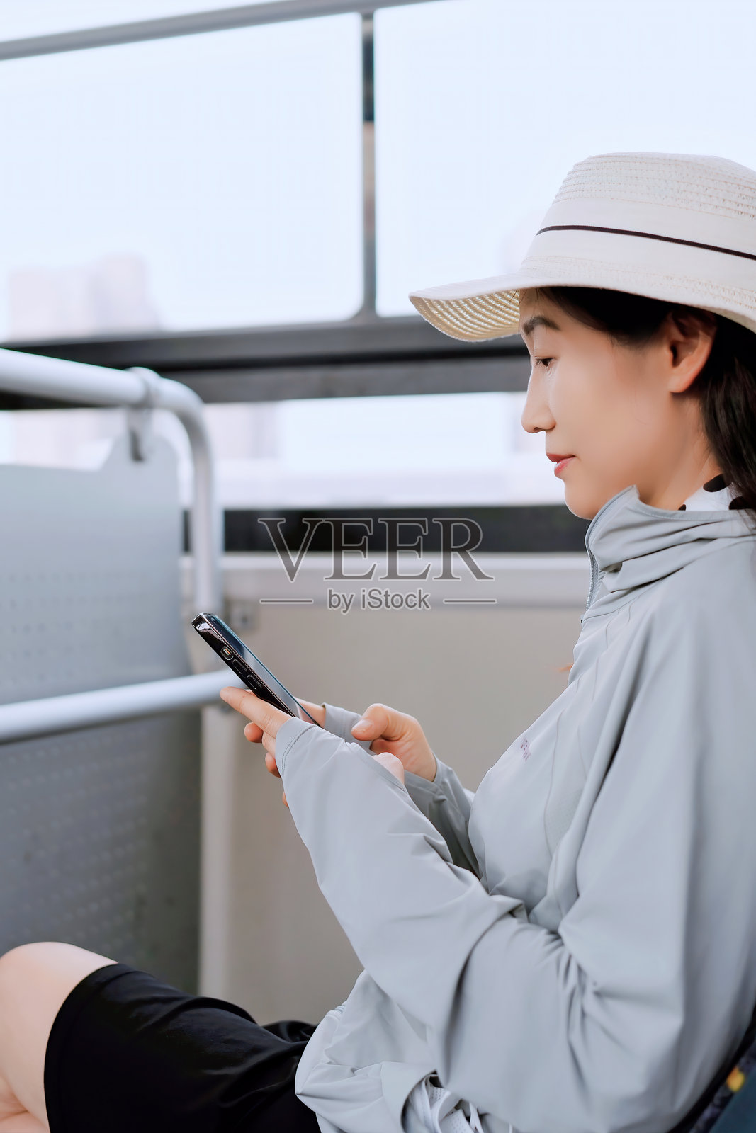 年轻女性在公共交通上享受放松时光，同时使用智能手机照片摄影图片