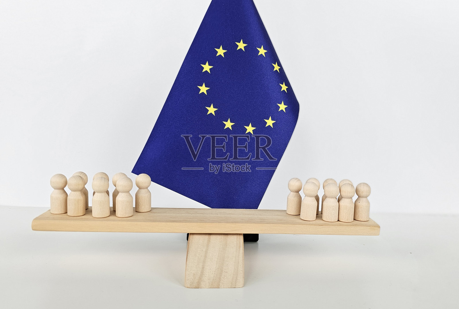 欧洲联盟概念，木制人物在欧盟旗帜上平衡，突显团结。照片摄影图片