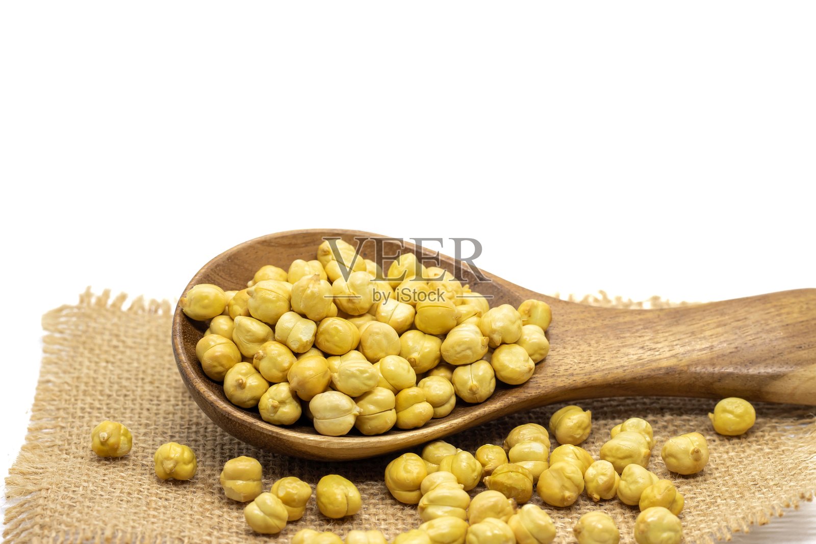 木勺中的烤鹰嘴豆或豆类，放在白色背景的麻布上，留有空白空间，也称为孟加拉豆或埃及豆。照片摄影图片