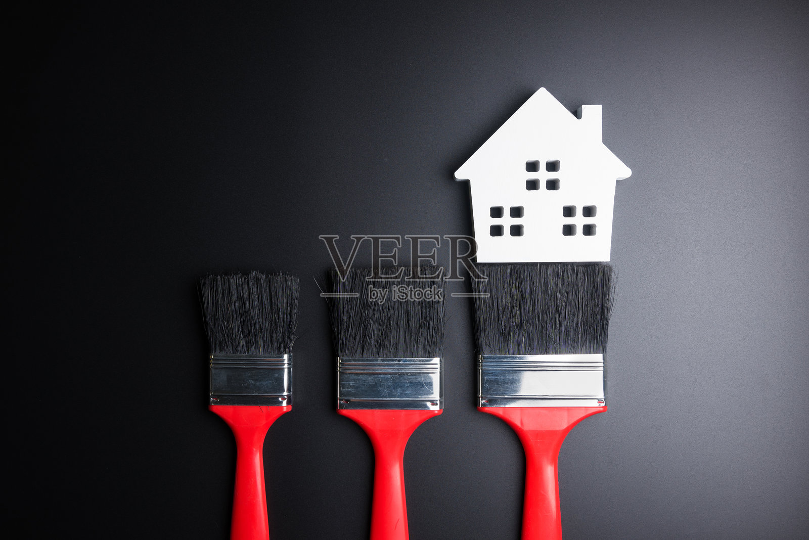 黑色背景下的画笔与模型房屋的俯视图照片摄影图片