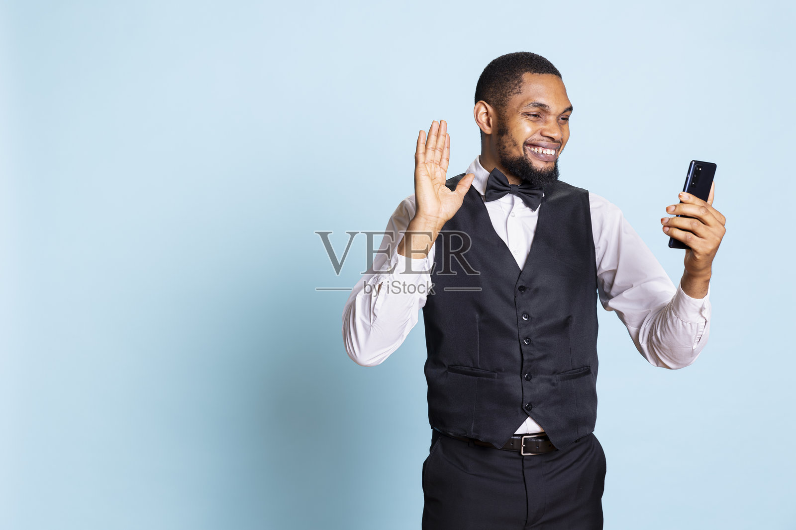 优雅的酒店门童在智能手机上接听视频电话照片摄影图片