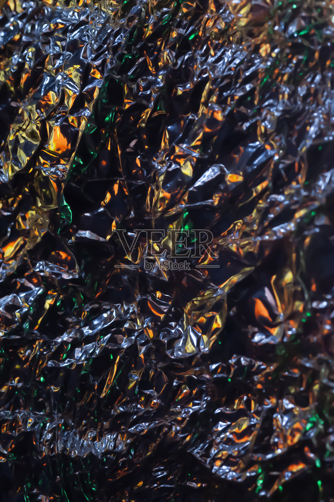 光滑表面。皱纹铝箔。皱纹背景。黑暗中的彩色光泽。照片摄影图片