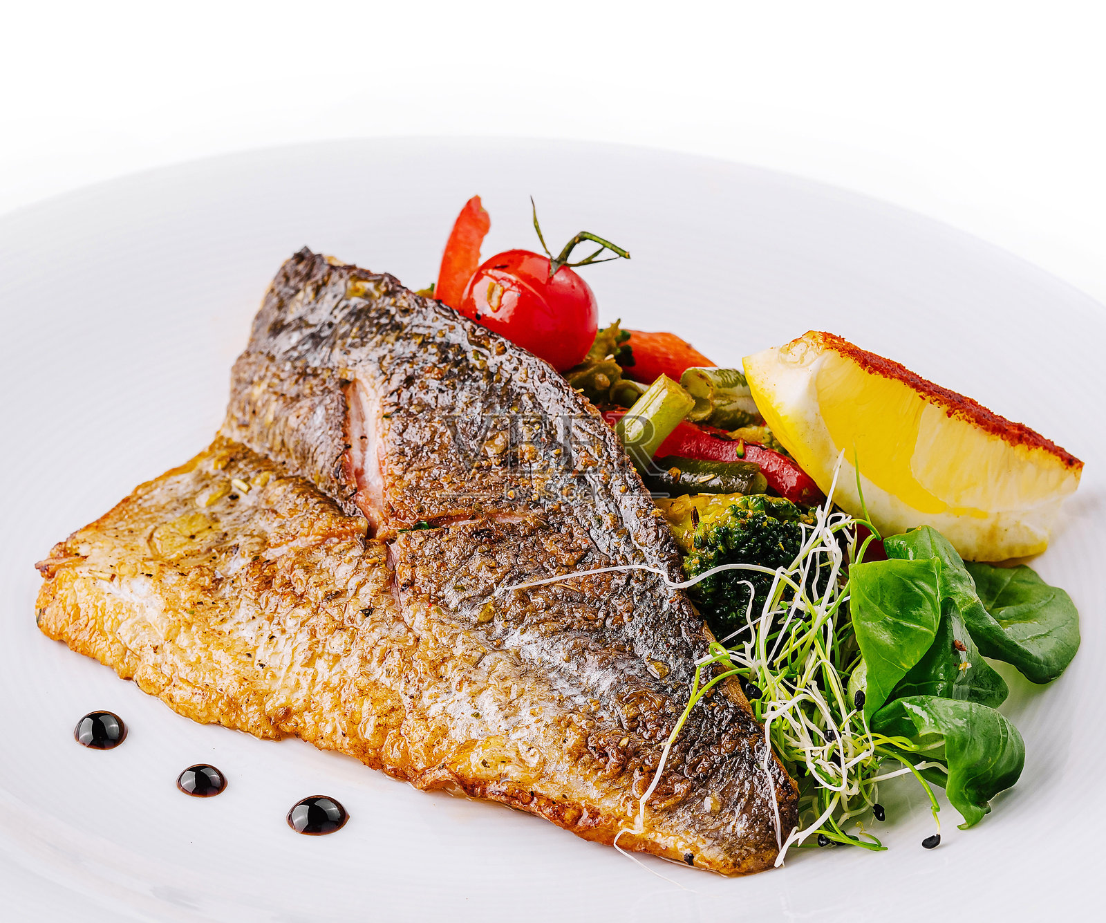 美味的烤鱼配蔬菜和柠檬，摆放在白色盘子上照片摄影图片