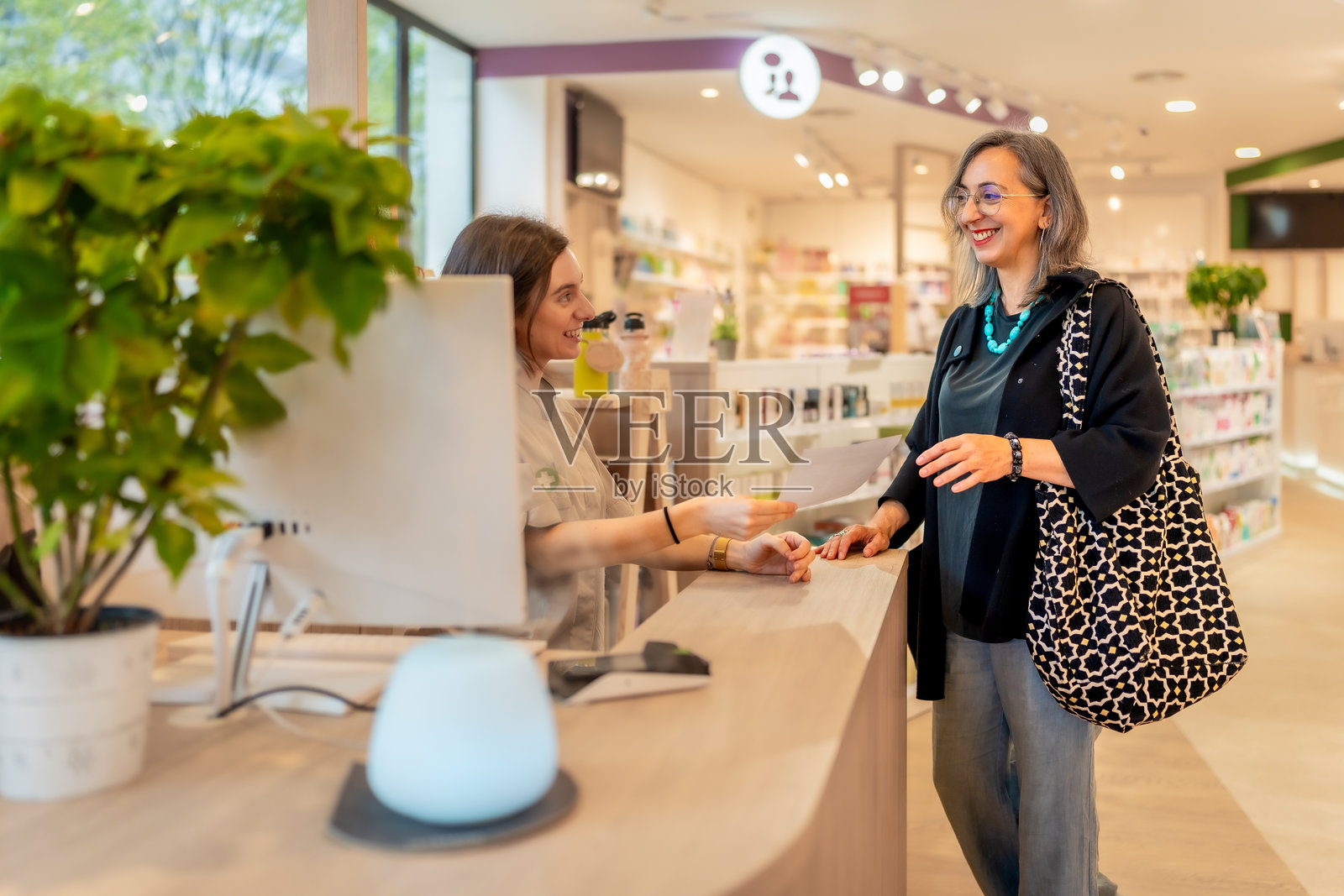 女性在商店里将药方递给药剂师照片摄影图片